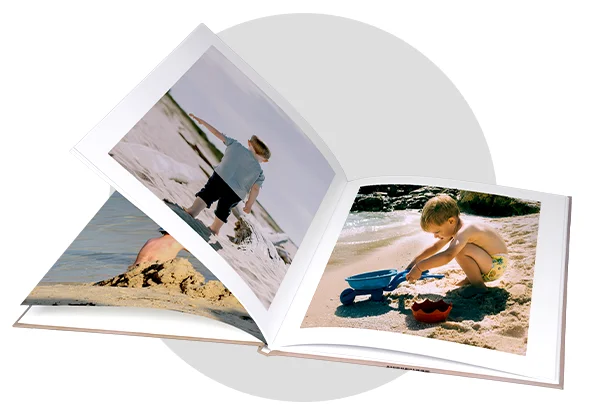 Open photo book showing beach scenes with a young child playing in the sand. Keep your memories forever – with your own custom photo book. 